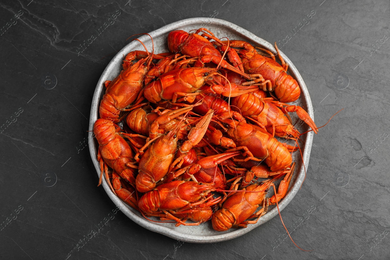 Photo of Delicious boiled crayfishes on black table, top view