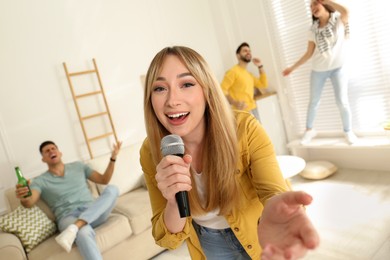 Photo of Young woman singing karaoke with friends at home