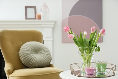 Photo of Beautiful tulips and burning candles on white table indoors, space for text. Interior design