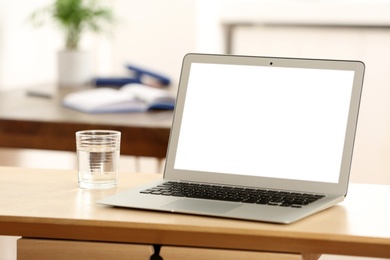 New modern laptop on wooden table in office. Space for text