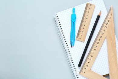 Photo of Different rulers and compass on light grey background, flat lay. Space for text