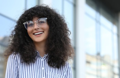 Portrait of beautiful woman in glasses outdoors. Attractive lady smiling and looking into camera. Space for text