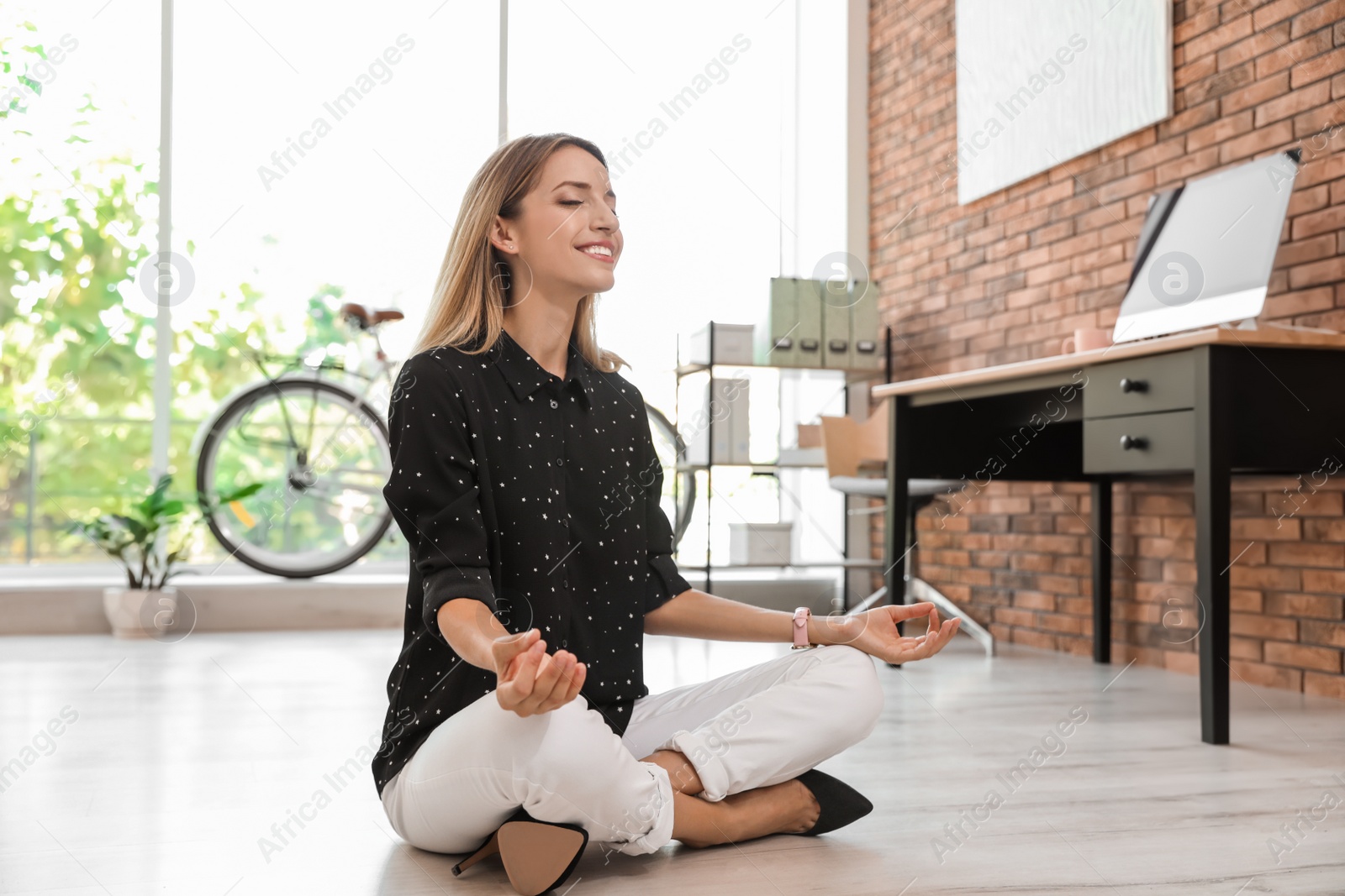 Photo of Young businessman doing yoga exercises in office. Workplace fitness