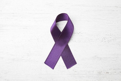 Purple ribbon on white wooden background, top view. Domestic violence awareness