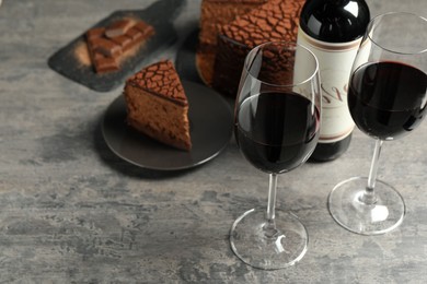 Photo of Delicious chocolate truffle cake and red wine on grey textured table