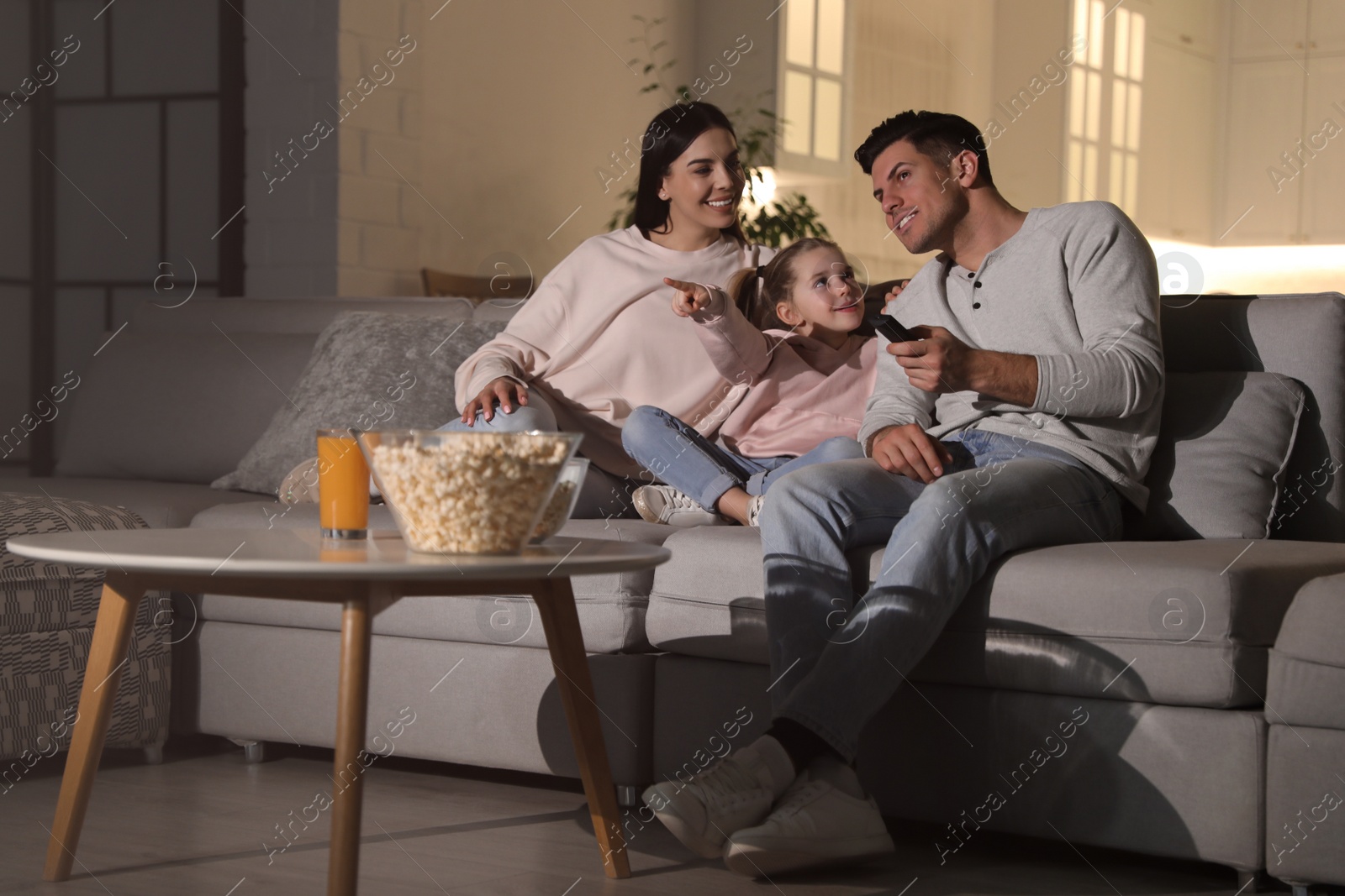 Photo of Family watching movie with popcorn on sofa at night