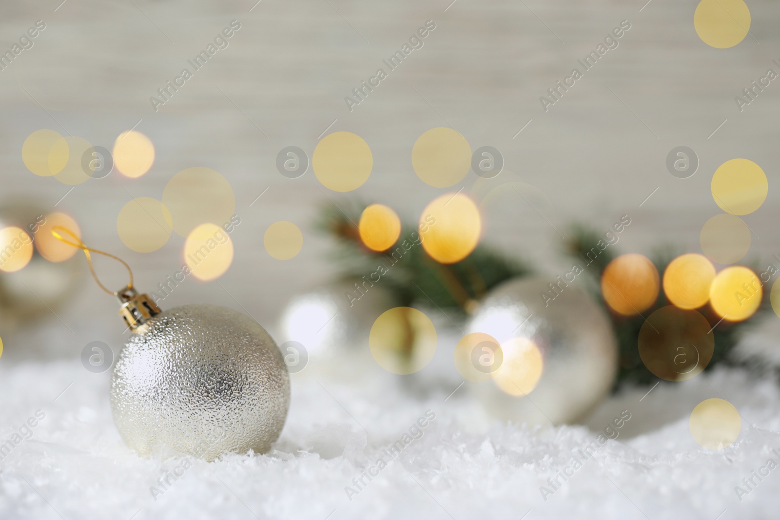 Image of Beautiful Christmas ball on snow against blurred background, space for text. Bokeh effect
