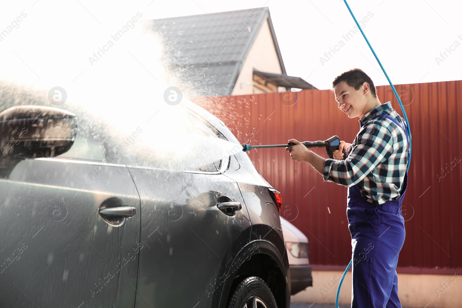 Photo of Worker cleaning automobile with high pressure water jet at car wash