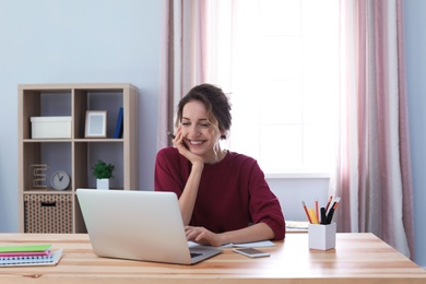 Photo of Young woman working with laptop at desk. Home office