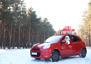 Photo of Authentic Santa Claus in red car with gift boxes, view from outside