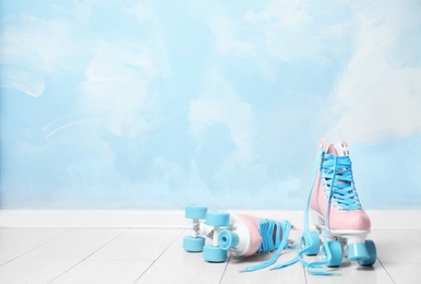 Photo of Vintage roller skates on floor near color wall. Space for text