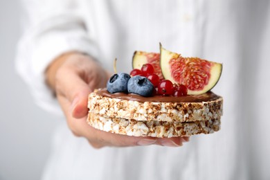 Photo of Woman holding tasty crispbreads with chocolate, berries and figs, closeup