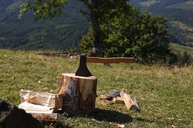 Photo of Tree stump with axe and cut firewood on hill