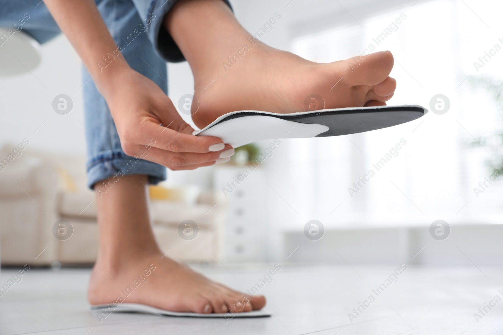 Photo of Woman fitting orthopedic insole at home, closeup