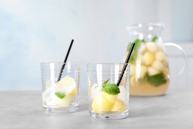 Photo of Glasses with melon balls and ice cubes on table. Preparing tasty drink