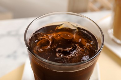 Photo of Refreshing iced coffee in glass on table, closeup