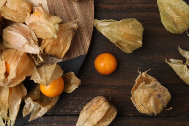 Ripe physalis fruits with calyxes on wooden table, flat lay