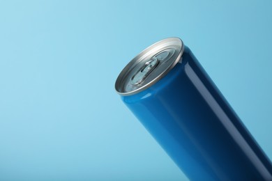 Can of energy drink on light blue background, closeup. Space for text