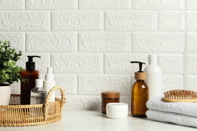 Photo of Different bath accessories and personal care products on white table near brick wall