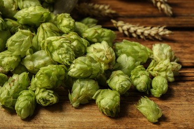 Fresh hop flowers and wheat ears on wooden table, closeup