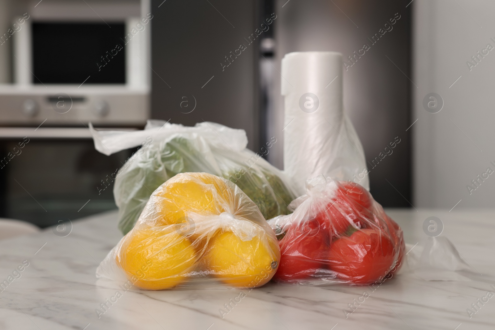 Photo of Plastic bags with different fresh products on white marble table in kitchen