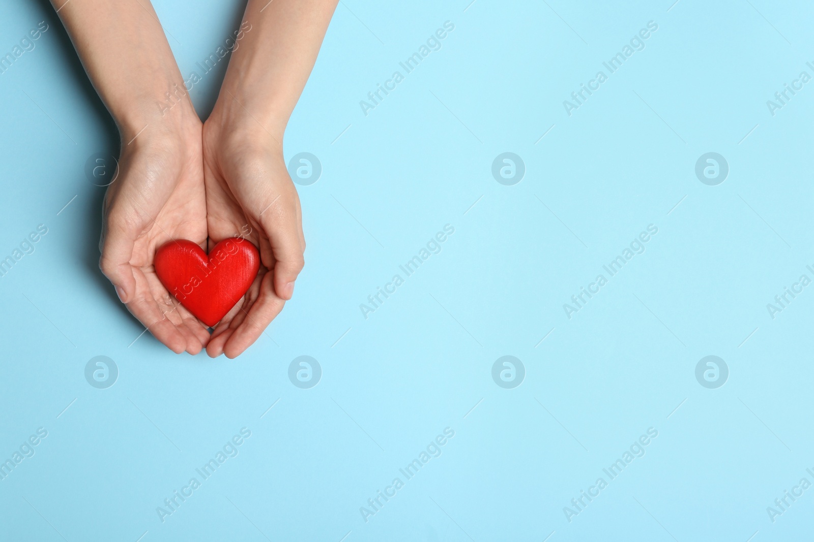 Photo of Woman holding heart on blue background, top view with space for text. Donation concept