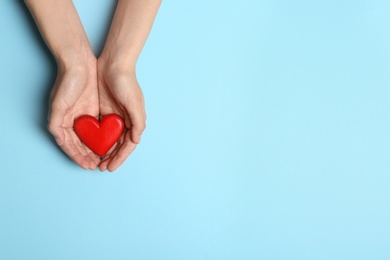 Woman holding heart on blue background, top view with space for text. Donation concept