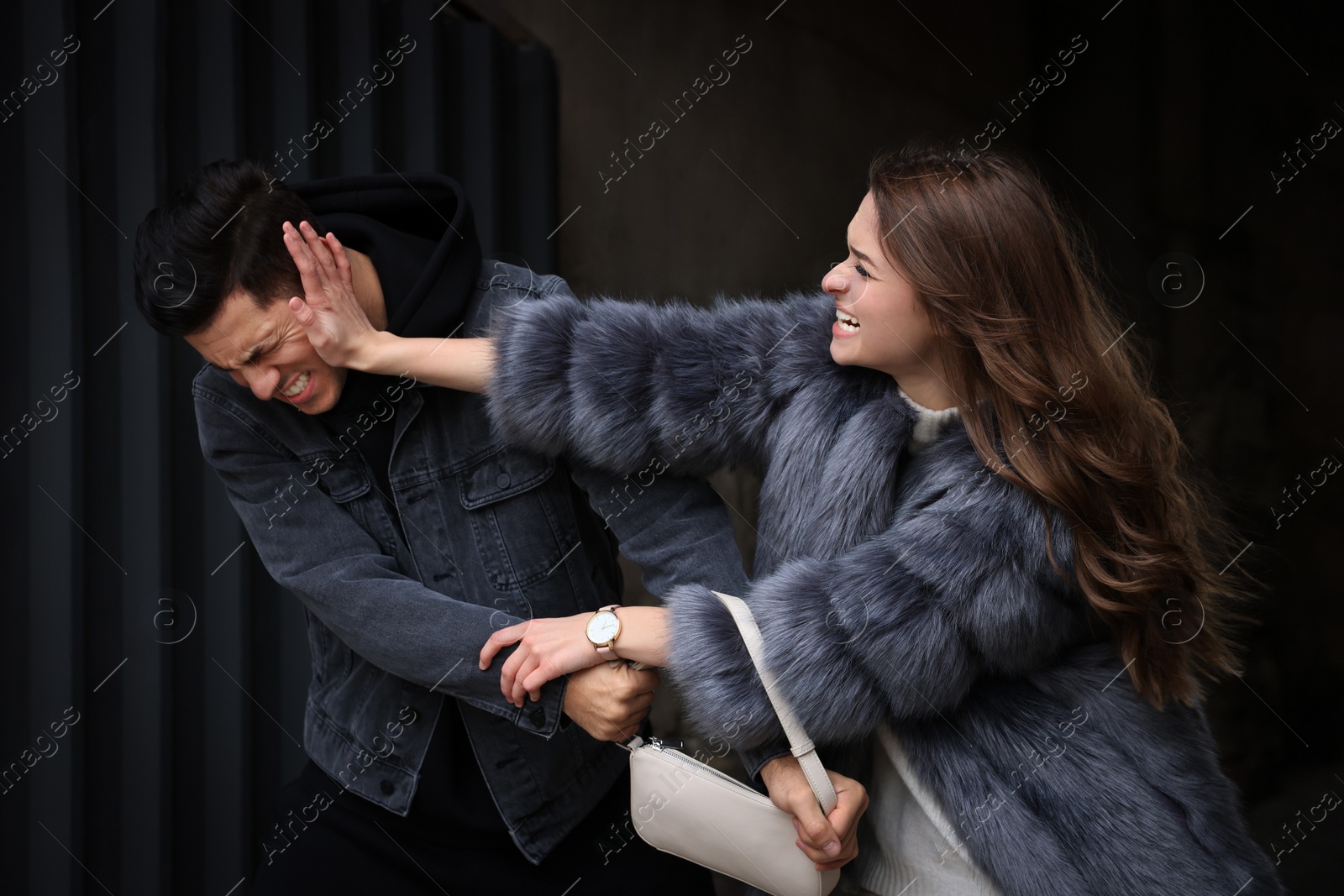 Photo of Woman fighting with thief while he trying to steal her bag in alley. Self defense concept