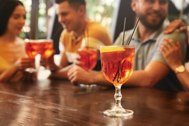 Friends resting together in restaurant, focus on glass with Aperol spritz cocktail
