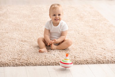 Photo of Children toys. Cute little boy and spinning top on rug at home