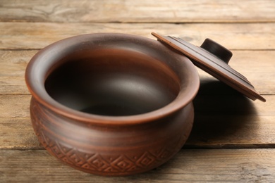 Clay pot with lid on wooden table