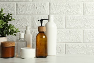 Photo of Bath accessories. Personal care products on white table near brick wall, space for text