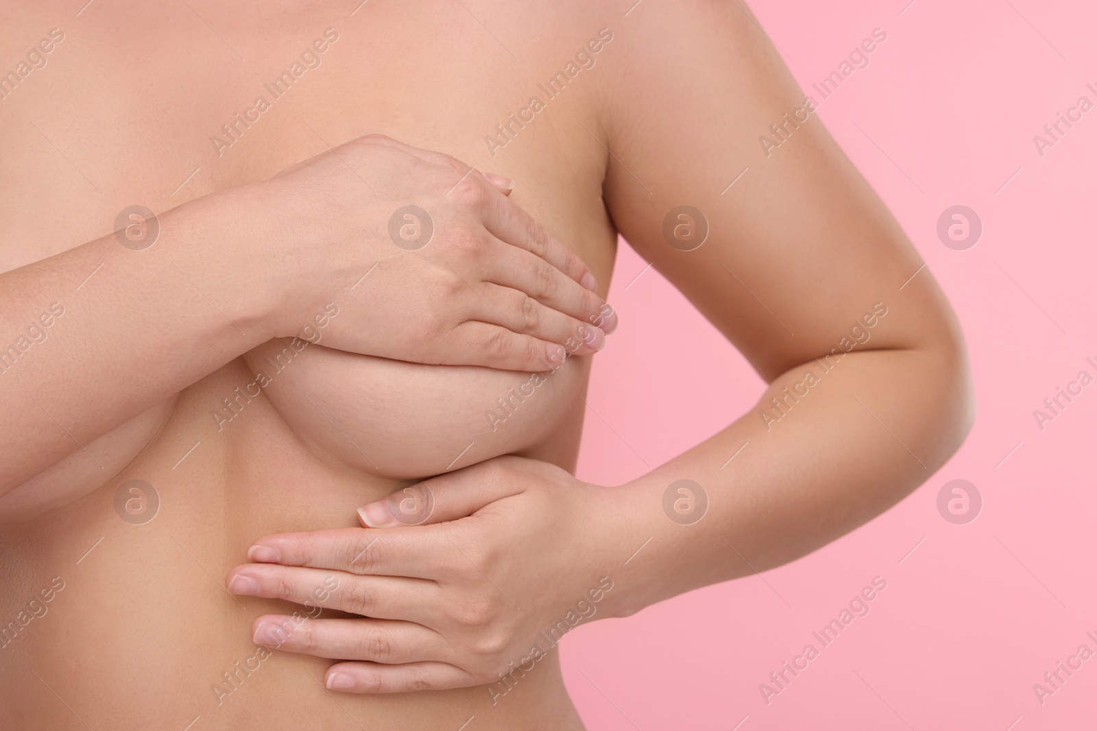 Photo of Mammology. Naked woman doing breast self-examination on pink background, closeup