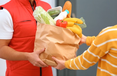 Photo of Male courier delivering food to client indoors, closeup