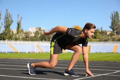 Sporty man ready for running at stadium on sunny morning