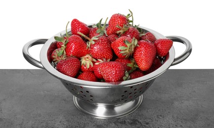 Photo of Metal colander with fresh strawberries on grey table against white background