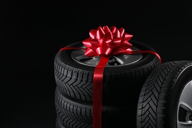 Photo of Gift set of wheels with winter tires on black background, closeup