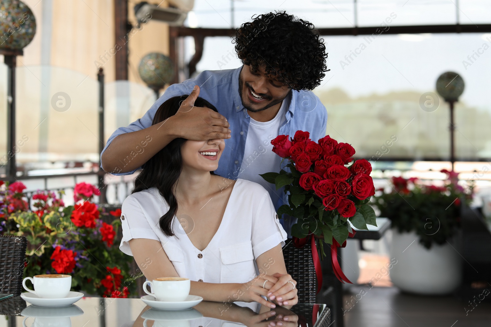 Photo of International dating. Handsome man presenting roses to his girlfriend in restaurant