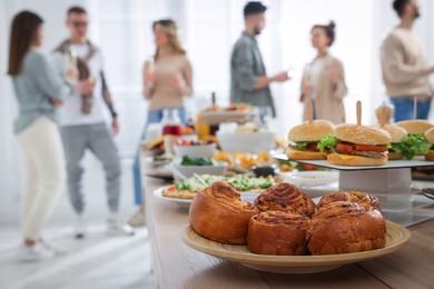 Photo of Brunch table setting with different delicious food	and blurred view of people on background