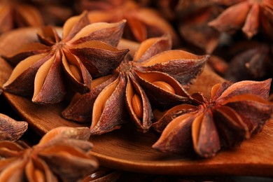 Photo of Aromatic anise stars and wooden spoon on table, closeup