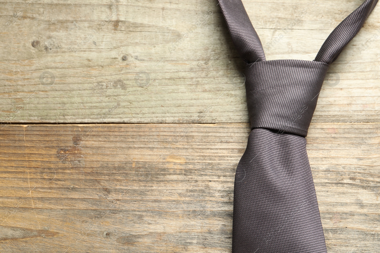 Photo of One necktie on light wooden table, top view. Space for text