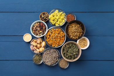 Photo of Many different dry herbs, flowers and seeds on blue wooden table, flat lay