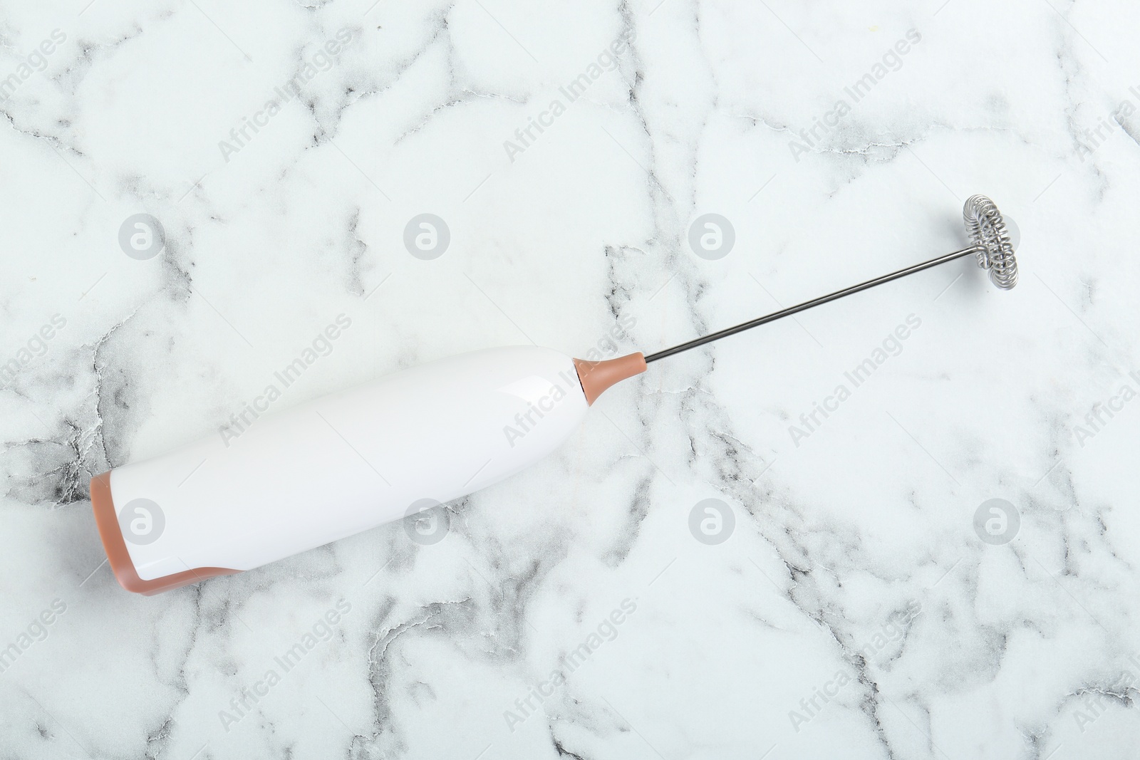 Photo of Milk frother wand on white marble table, top view