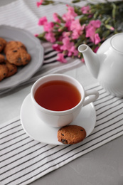 Photo of Cup of aromatic tea and tasty cookies on grey table