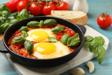 Photo of Delicious Shakshuka served on light blue wooden table, closeup