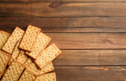 Many delicious crackers on wooden table, flat lay. Space for text