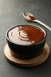 Photo of Tasty barbeque sauce in bowl on dark table, closeup