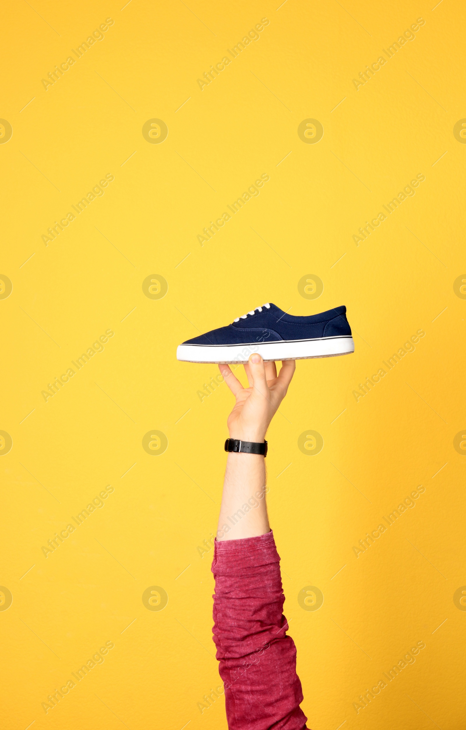 Photo of Man holding stylish shoe on yellow background, closeup