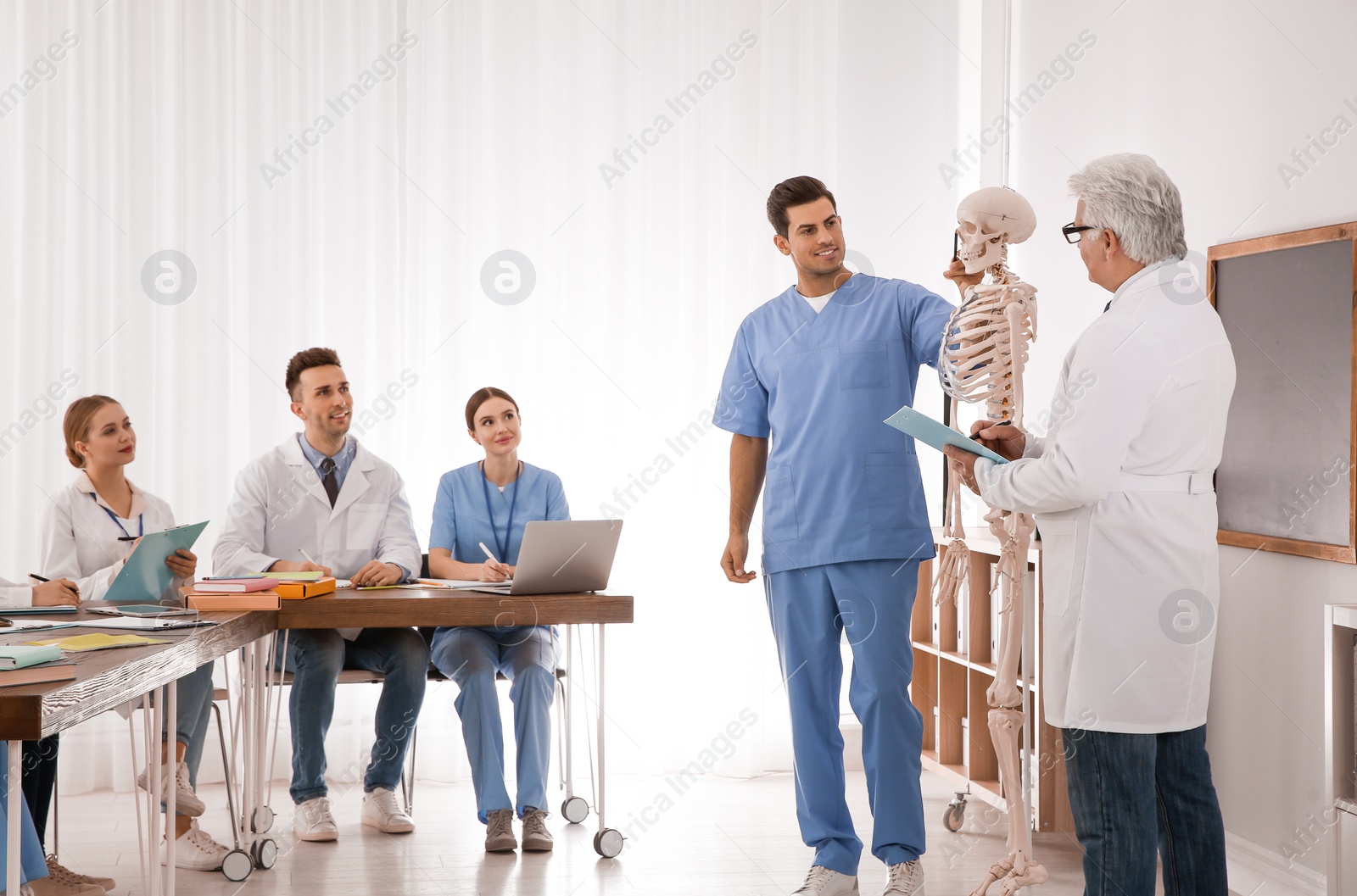 Photo of Medical students and professor studying human skeleton anatomy in classroom