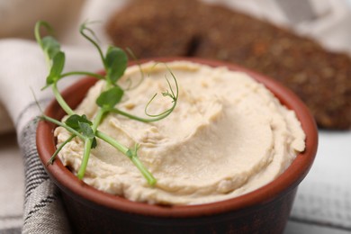 Bowl of delicious hummus on table, closeup